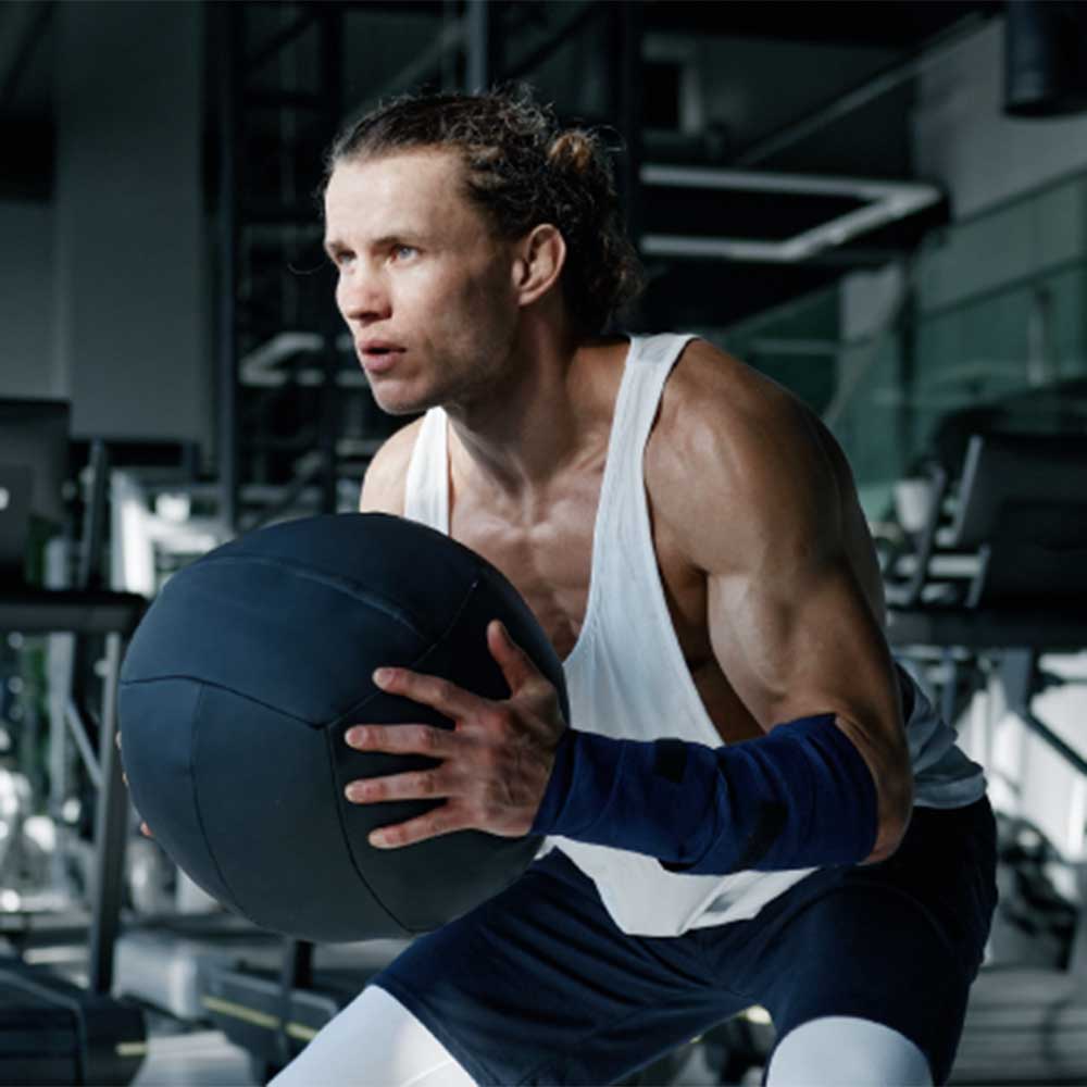 Dedicated gym-goer using a medicine ball at GYMVMT